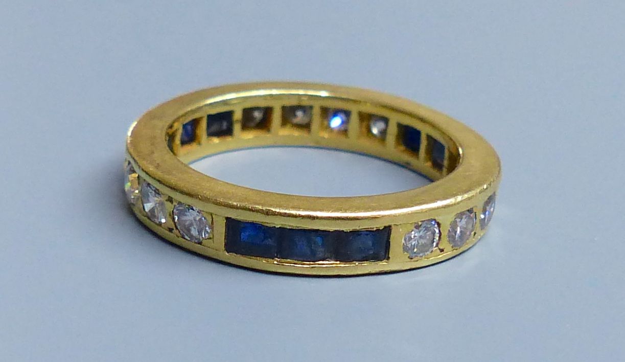 A modern yellow metal (tests as 18ct), sapphire and diamond set full eternity ring, size 0, gross 6.3 grams.